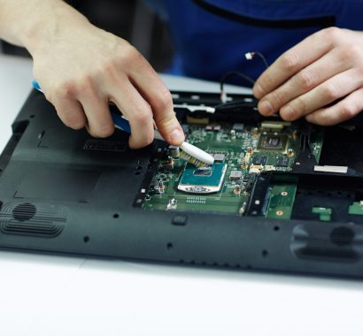 Closeup shot of male hands working on disassembling and cleaning circuit board in laptop using brush